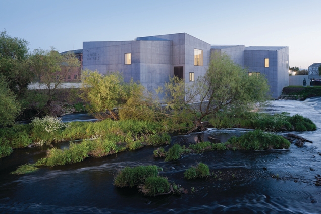 The building emerges from the bottom of a weir at a bend in the River Calder.