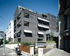 The building in summer mode, with loggias open, shades down, and its sibling behind on the left.