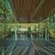 The sloping corridor between the public and private rooms is lined with mirror-polished steel, reflecting the woodland outside.